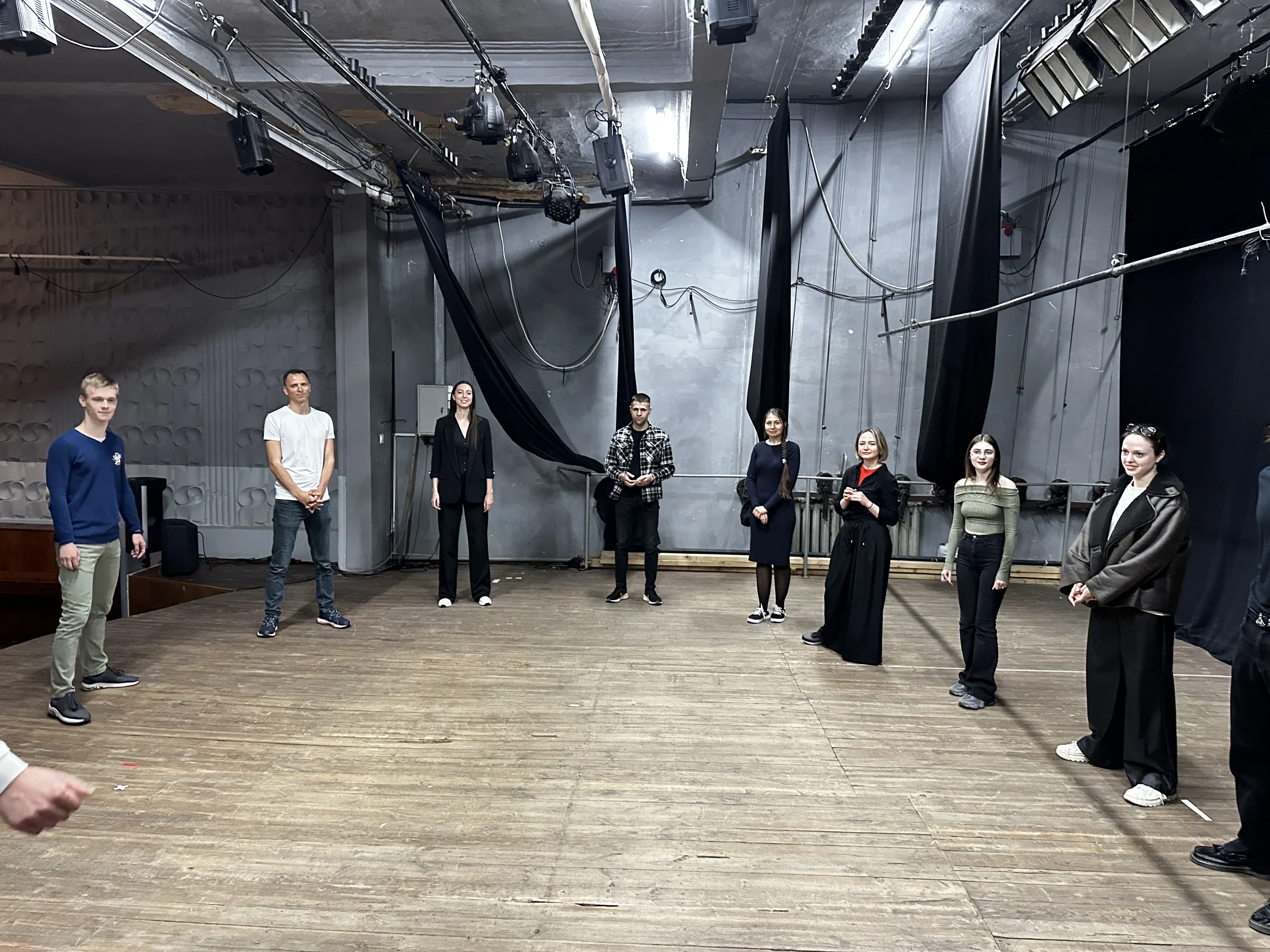 Adulți exersând prezența și contactul într-un cerc, într-o sală de teatru.
